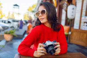 Fashionable woman in red sweater posing in cafe.